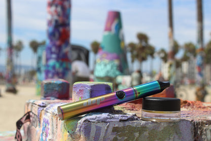 Lunar dab pen in rainbow metallic with cannabis concentrates at the beach.